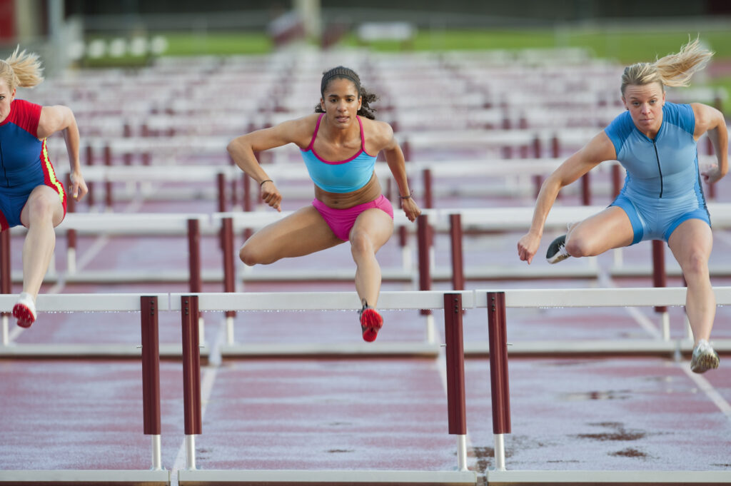 Runners jumping hurdles in race